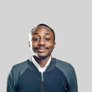 Smiling young man in casual attire against a plain background.