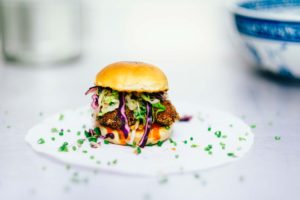 Gourmet pulled pork sandwich with colorful slaw on a white plate.