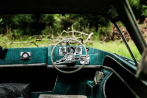 Rustic view through the steering wheel of an old, worn car.