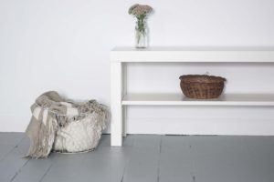 Minimalist white bench with a basket and flowers in a glass jar.