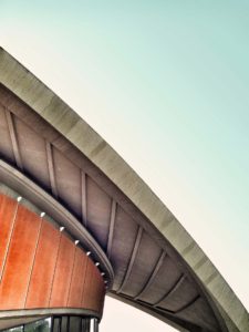 Curved architectural structure with wooden panels and a clear sky background.