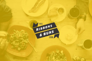 Logo for Ribbons & Buns, established in 1984, with food background.