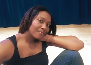 A woman relaxing with a slight smile, resting her head on her hand.