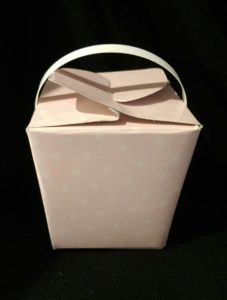 A pink paper gift box with a handle and a folded top.