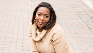 Smiling woman wearing a beige sweater outdoors.