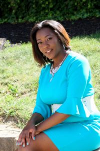 Woman in a bright blue dress sitting outdoors on grass.