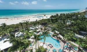 A tropical resort with a large pool and beach view.