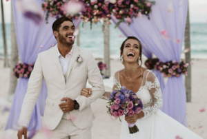 Joyful couple celebrating their wedding day under floral decorations.